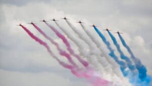 Foto van negen straaljagers die een kleurenspoor na laten in de kleuren rood, wit en blauw.