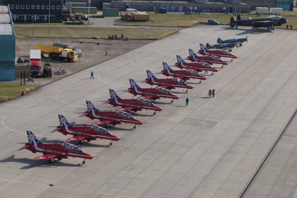 Foto van tien straaljagers en twee andere vliegtuigen die in een rij naast elkaar opgesteld staan op een landingsbaan.