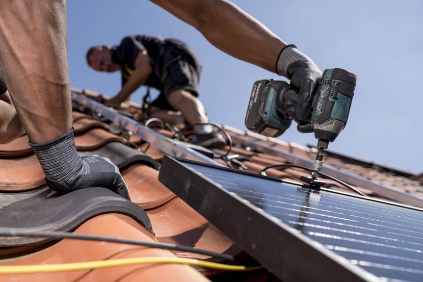 Foto van twee installateurs die zonnepanelen monteren op een dak